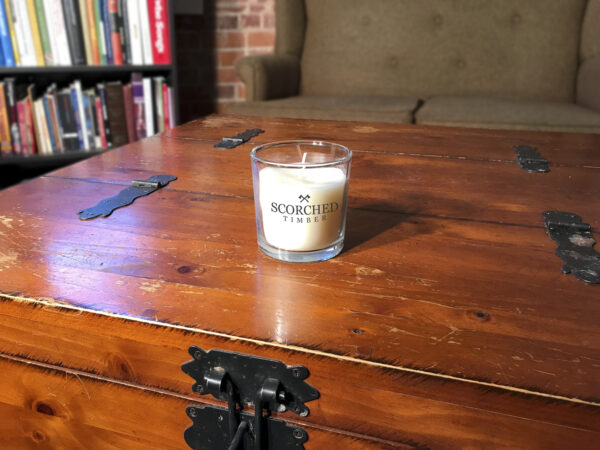 Scorched Timber candle sitting on large wooden chest in apartment