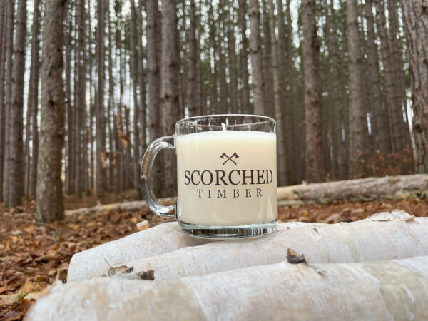 Scorched Timber Mug sitting on some firewood in forrest